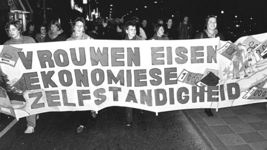 Vrouwen lopen in een demonstratie met een spandoek waarop alternatieve spelling wordt gebruikt